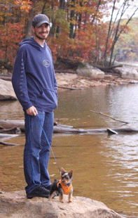 Image of man with small dog at river